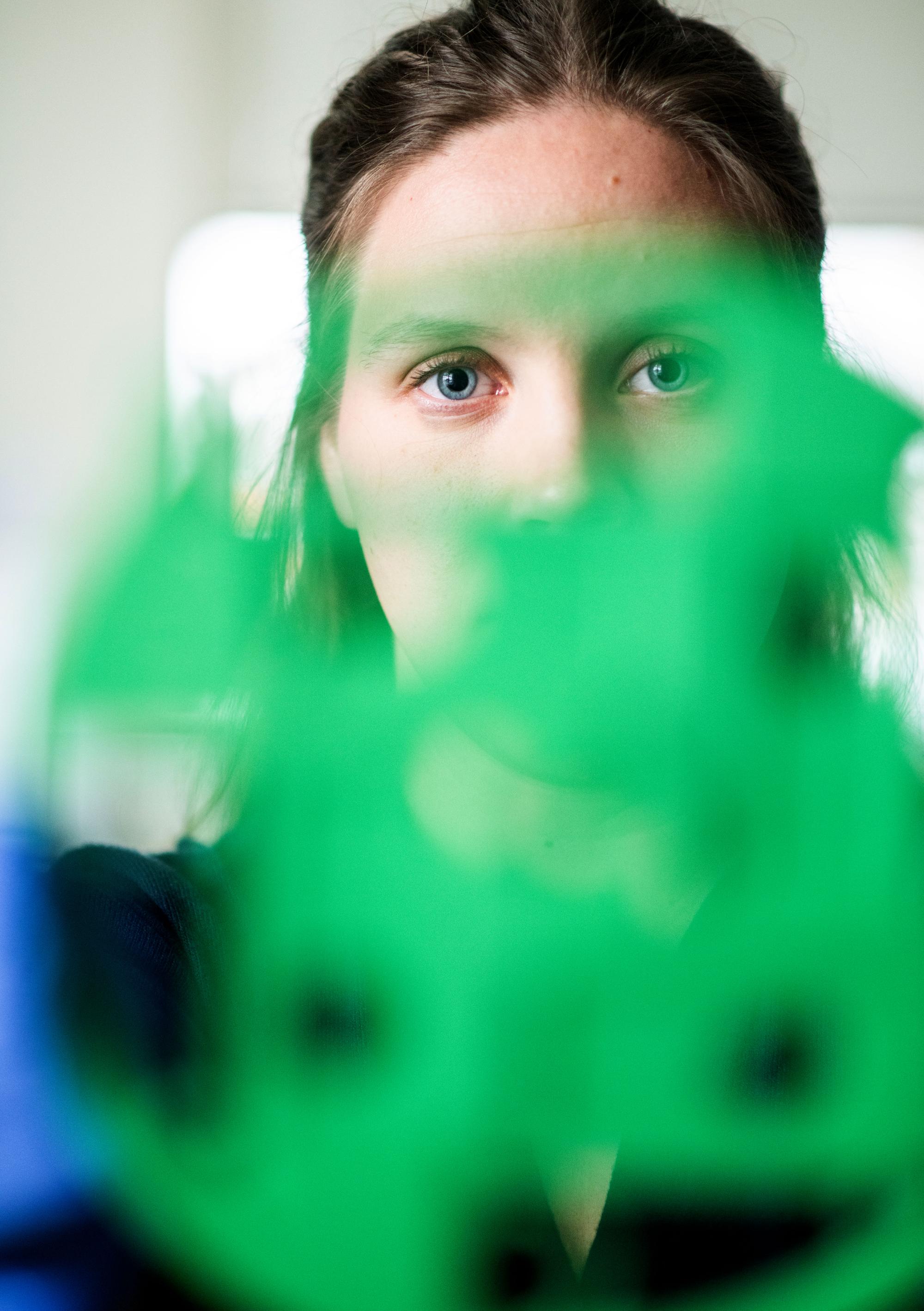 Student researcher looking through a green sculpture.